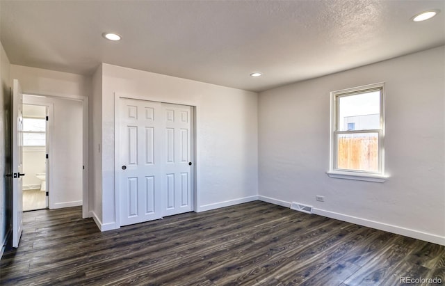 unfurnished bedroom with multiple windows, a closet, and dark hardwood / wood-style floors