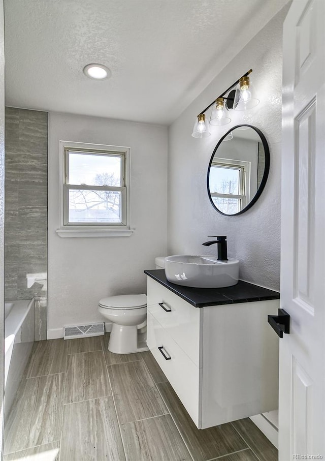 full bathroom with a textured ceiling, vanity, bathing tub / shower combination, and toilet