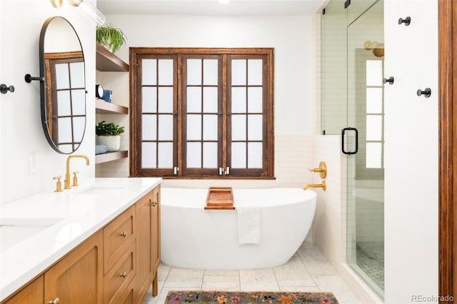 bathroom with double vanity, a freestanding tub, tile patterned flooring, a stall shower, and a sink