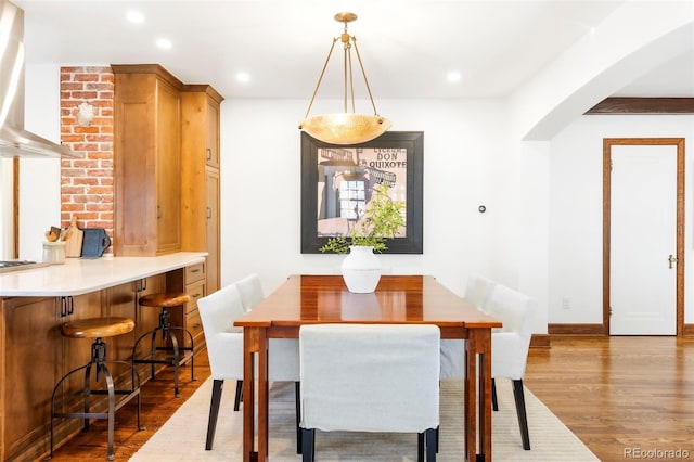 dining area featuring recessed lighting, arched walkways, and wood finished floors