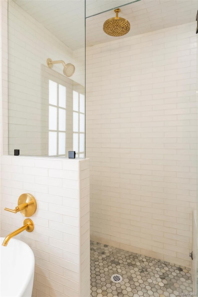 bathroom featuring tile patterned flooring, a tile shower, and tile walls
