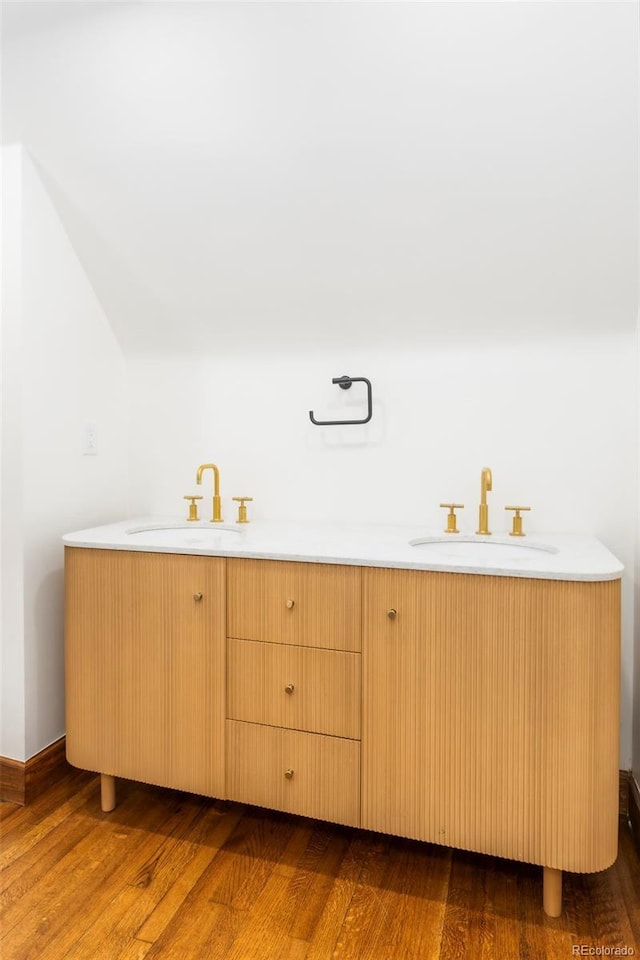 bathroom featuring double vanity, a sink, and wood finished floors