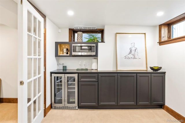 bar featuring light colored carpet, stainless steel microwave, wine cooler, visible vents, and a bar
