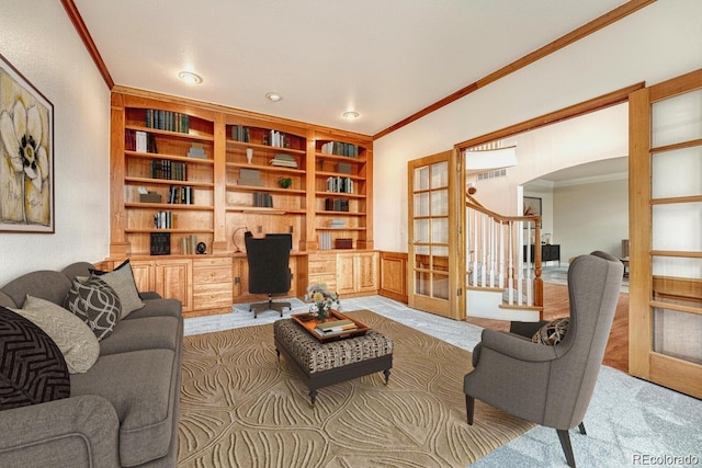 carpeted living room featuring french doors, ornamental molding, and built in desk