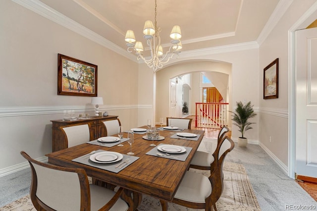 dining space featuring a chandelier, light colored carpet, ornamental molding, and a raised ceiling