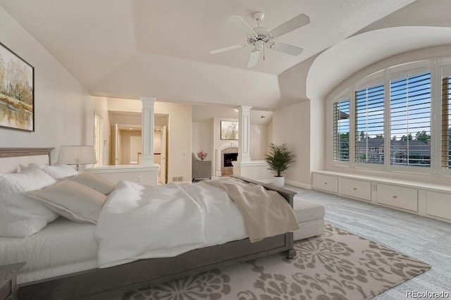 bedroom with ensuite bath, light colored carpet, vaulted ceiling, ceiling fan, and decorative columns