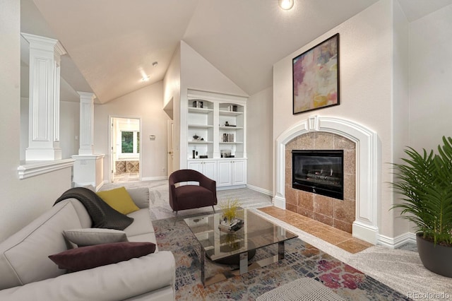 living room featuring built in shelves, lofted ceiling, a fireplace, and ornate columns