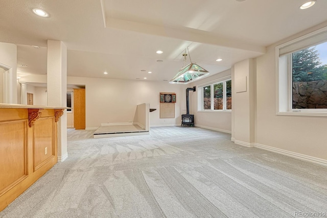 unfurnished living room with light carpet and a wood stove