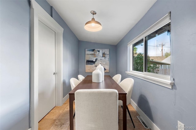 dining room with light tile patterned floors and vaulted ceiling