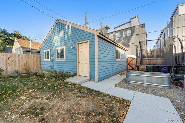 rear view of property with a lawn and a trampoline