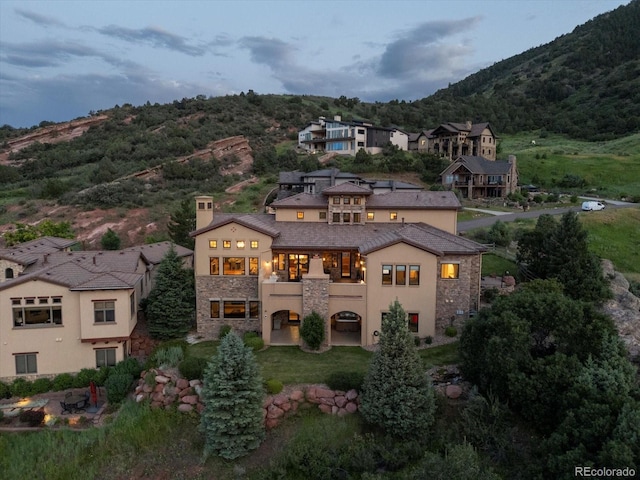 17121 Snow Creek Ln, Morrison, CO 80465 - rear view of property featuring a balcony, stone siding, a mountain view, stucco siding, and a chimney