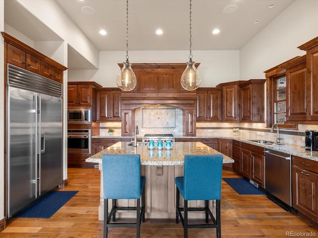 17121 Snow Creek Ln, Morrison, CO 80465 - kitchen with built in appliances, a center island with sink, decorative backsplash, wood finished floors, and recessed lighting