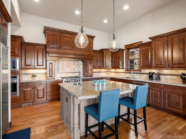 17121 Snow Creek Ln, Morrison, CO 80465 - kitchen featuring tasteful backsplash, an island with sink, light wood-type flooring, and recessed lighting