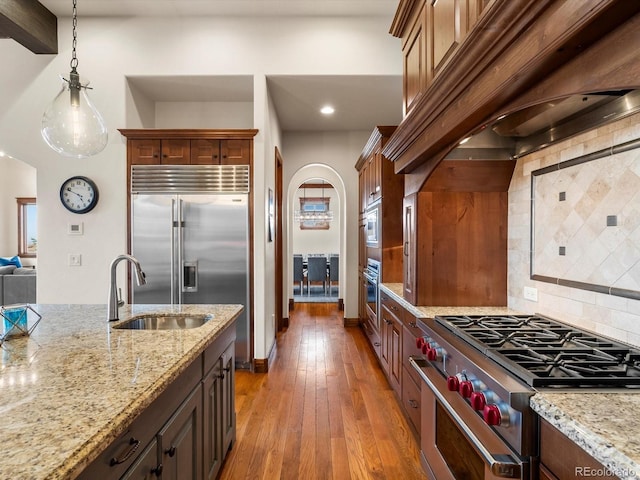 17121 Snow Creek Ln, Morrison, CO 80465 - kitchen with built in appliances, arched walkways, light stone counters, tasteful backsplash, and recessed lighting