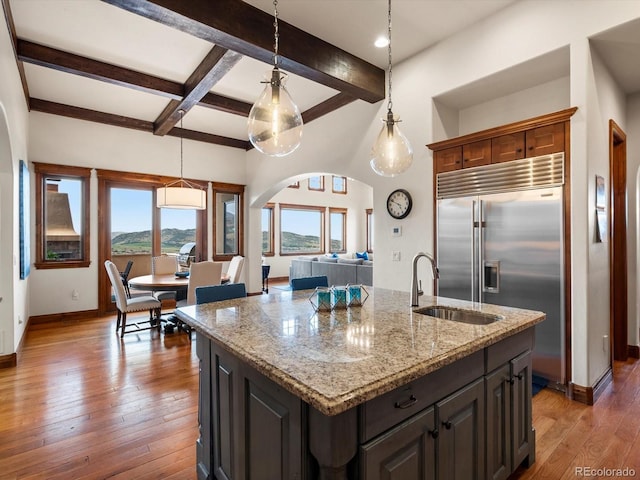 17121 Snow Creek Ln, Morrison, CO 80465 - kitchen with stainless steel built in fridge, beamed ceiling, pendant lighting, hardwood / wood-style floors, and light stone counters
