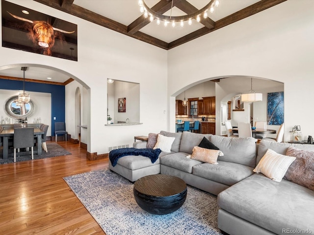 17121 Snow Creek Ln, Morrison, CO 80465 - living room with arched walkways, wood finished floors, beamed ceiling, a chandelier, and a high ceiling