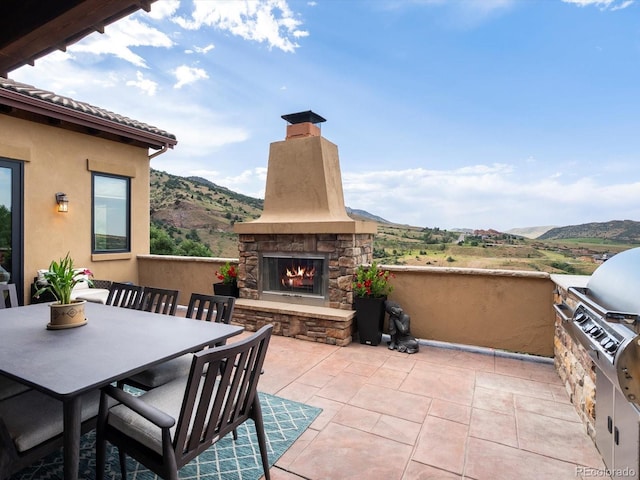 17121 Snow Creek Ln, Morrison, CO 80465 - view of patio with an outdoor stone fireplace, a mountain view, outdoor dining area, and area for grilling