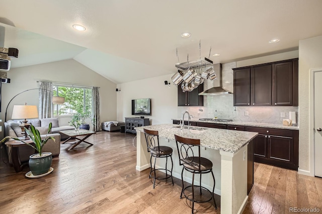853 Jenny Ln, Berthoud, CO 80513 - kitchen with open floor plan, wall chimney range hood, a sink, dark brown cabinets, and vaulted ceiling