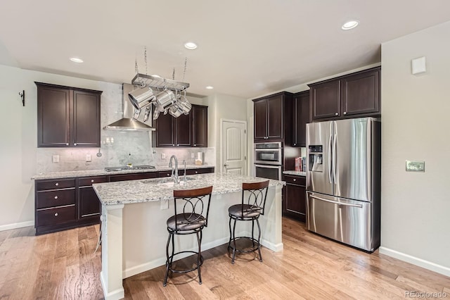 853 Jenny Ln, Berthoud, CO 80513 - kitchen featuring stainless steel appliances, wall chimney range hood, a sink, light wood-type flooring, and dark brown cabinetry