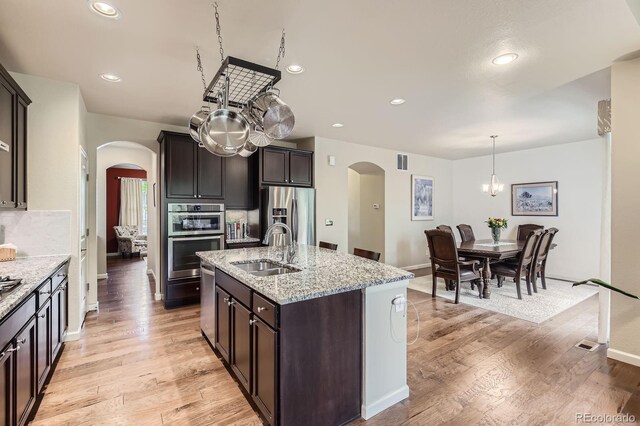 853 Jenny Ln, Berthoud, CO 80513 - kitchen with arched walkways, stainless steel appliances, a sink, light stone counters, and recessed lighting