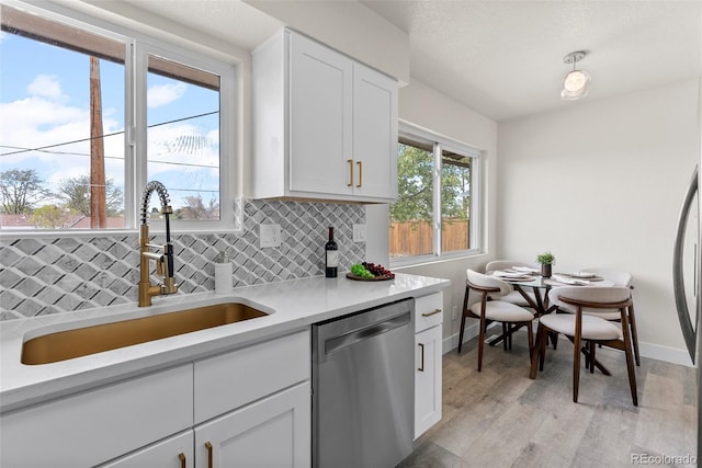 7961 Granada Rd, Denver, CO 80221 - kitchen with stainless steel dishwasher, tasteful backsplash, a sink, light countertops, and light wood finished floors