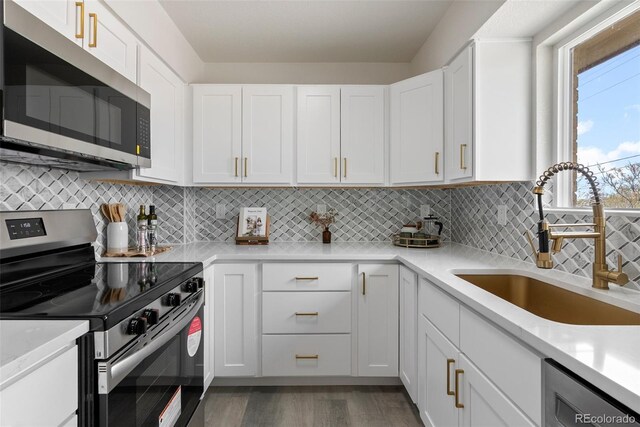 7961 Granada Rd, Denver, CO 80221 - kitchen with appliances with stainless steel finishes, a sink, light wood-style floors, and white cabinets