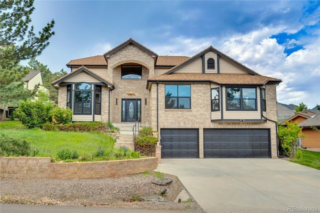 5569 Willow Springs Dr, Morrison, CO 80465 - view of front of house with concrete driveway, a garage, brick siding, roof with shingles, and a front lawn