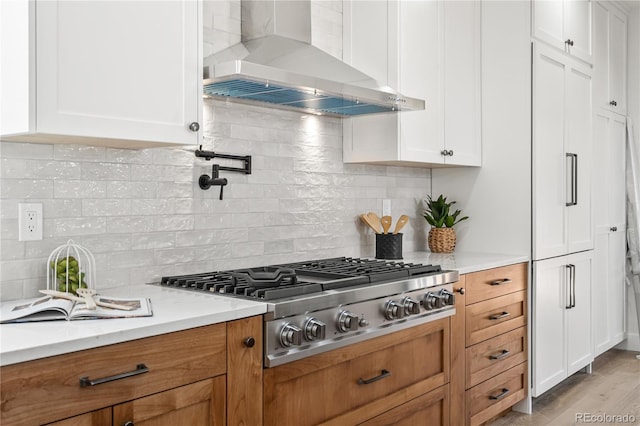 5569 Willow Springs Dr, Morrison, CO 80465 - kitchen featuring wall chimney range hood, stainless steel gas cooktop, white cabinets, and decorative backsplash