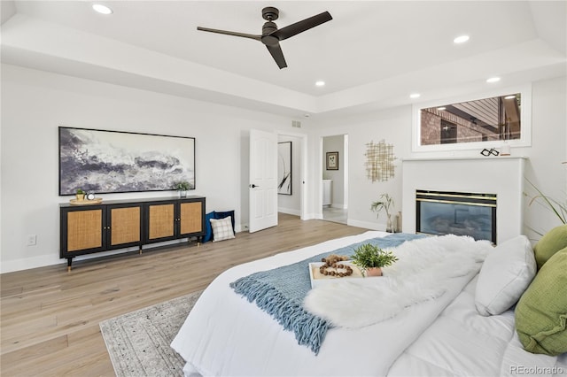 5569 Willow Springs Dr, Morrison, CO 80465 - bedroom featuring a tray ceiling, recessed lighting, wood finished floors, a glass covered fireplace, and ceiling fan