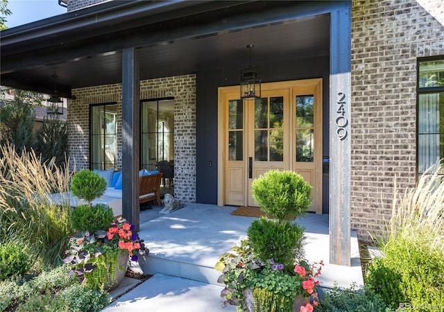 property entrance featuring covered porch and brick siding