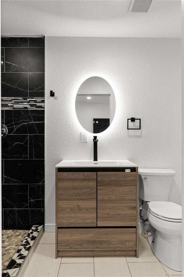 full bath featuring toilet, a tile shower, vanity, and tile patterned floors