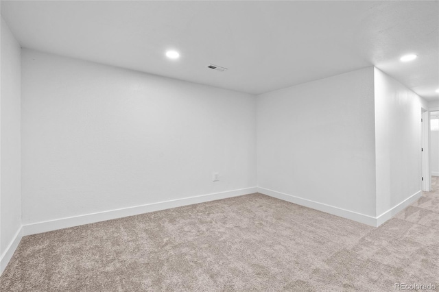 empty room featuring light colored carpet, recessed lighting, and baseboards
