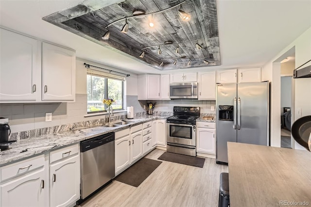 3235 S Newland St, Denver, CO 80227 - kitchen with stainless steel appliances, light wood-type flooring, white cabinetry, and decorative backsplash