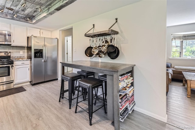 3235 S Newland St, Denver, CO 80227 - kitchen with appliances with stainless steel finishes, light wood-style floors, white cabinets, and tasteful backsplash