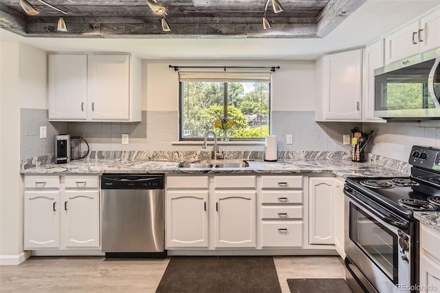 3235 S Newland St, Denver, CO 80227 - kitchen with stainless steel appliances, white cabinetry, light wood-style floors, and decorative backsplash