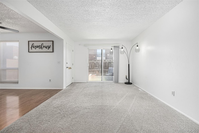 carpeted spare room with baseboards, a textured ceiling, ceiling fan, and wood finished floors