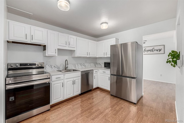 kitchen featuring light wood-style flooring, a sink, stainless steel appliances, light countertops, and white cabinetry