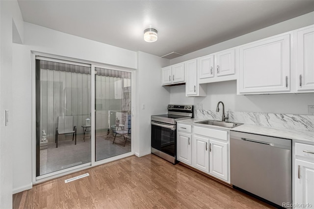 kitchen with visible vents, a sink, light wood-style floors, appliances with stainless steel finishes, and white cabinets