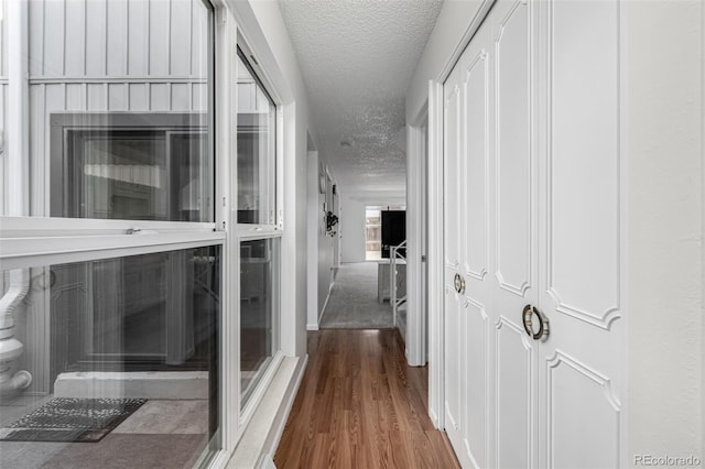 hall with wood finished floors and a textured ceiling