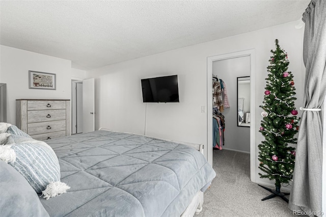 bedroom featuring a walk in closet, light colored carpet, a closet, and a textured ceiling