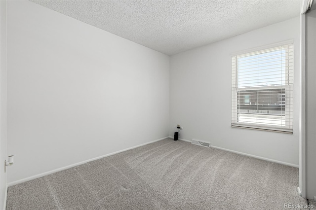 spare room with carpet flooring, baseboards, visible vents, and a textured ceiling