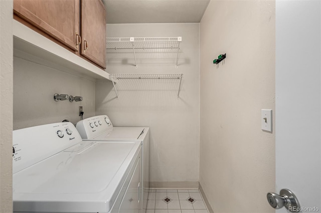 laundry area featuring washer and dryer, baseboards, cabinet space, and light tile patterned floors