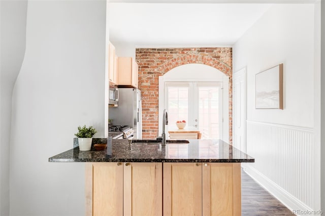 3346 W 30th Ave, Denver, CO 80211 - kitchen with light brown cabinets, appliances with stainless steel finishes, dark stone counters, a peninsula, and wood finished floors
