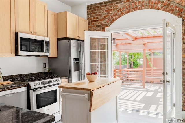 3346 W 30th Ave, Denver, CO 80211 - kitchen with appliances with stainless steel finishes, light brown cabinetry, healthy amount of natural light, brick wall, and butcher block countertops