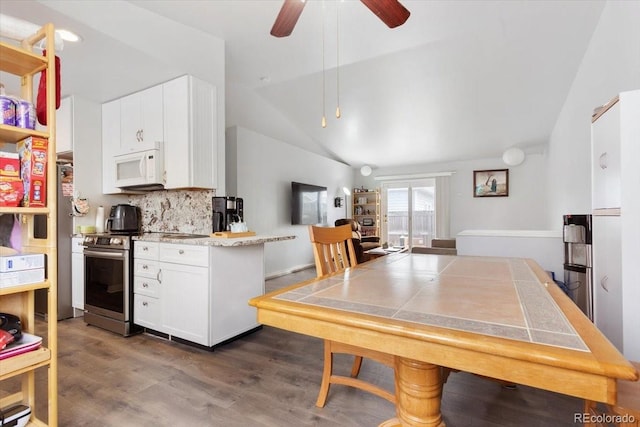 kitchen with lofted ceiling, backsplash, dark wood-type flooring, white cabinets, and stainless steel range oven