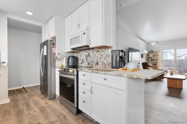 kitchen featuring appliances with stainless steel finishes, a kitchen breakfast bar, dark wood-type flooring, white cabinets, and decorative backsplash