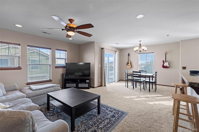 living room featuring light colored carpet, visible vents, a textured ceiling, baseboards, and ceiling fan with notable chandelier