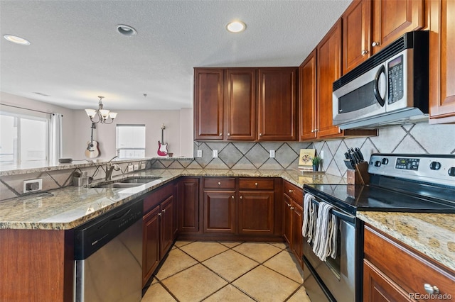 kitchen featuring a peninsula, stainless steel appliances, a sink, and light tile patterned flooring