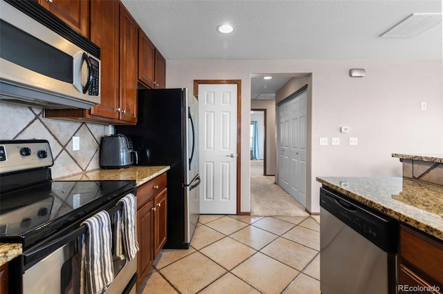 kitchen with stainless steel appliances, visible vents, light stone counters, and tasteful backsplash