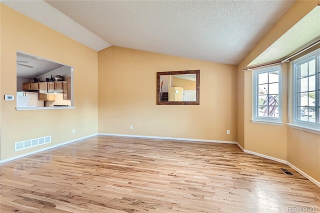 unfurnished living room featuring light hardwood / wood-style floors, a textured ceiling, ceiling fan, and vaulted ceiling